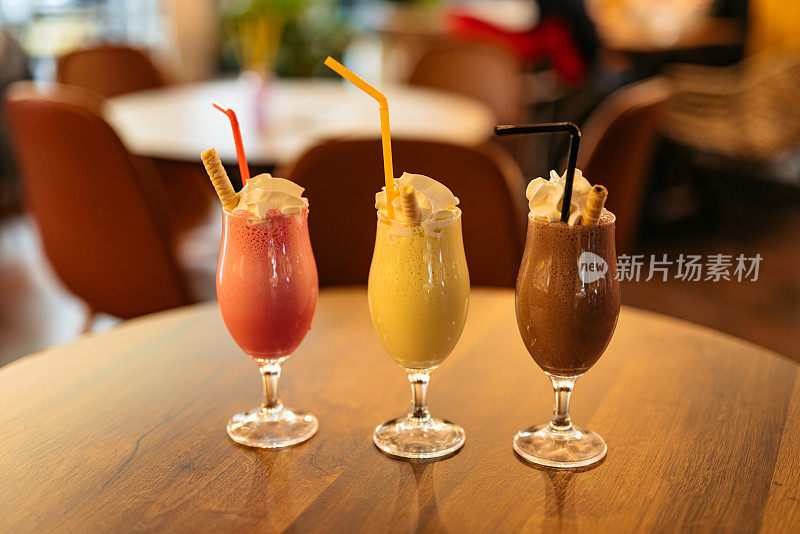 Strawberry, Vanilla And Chocolate Milkshake On A Table In A Café